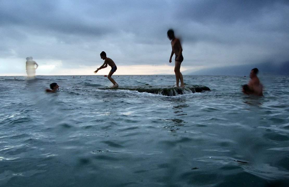 A group of children use a partially submerged concrete block, that stands in the sea just off the Black Sea resort of Gagra, as a platform from which to dive into the water.